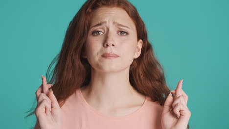 redheaded girl in front of camera on turquoise background.