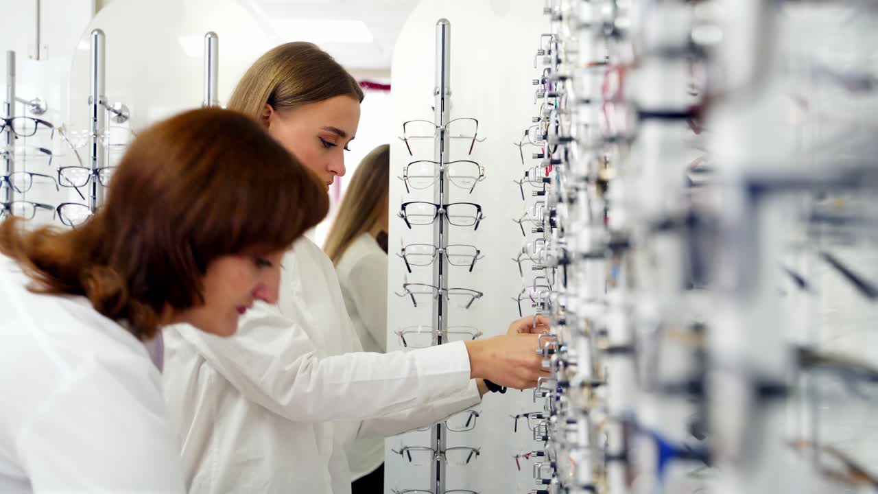 Lovely girl choosing glasses in the store. Attractive young woman buying fashionable eyeglasses. Vision and health care concept.