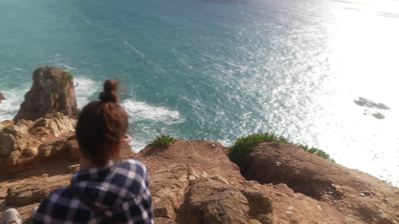 Woman enjoying a view from a cliff overlooking the ocean