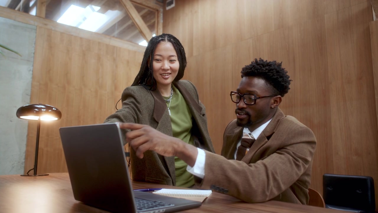 Diverse Business Professionals Discussing Information on Laptop in Office