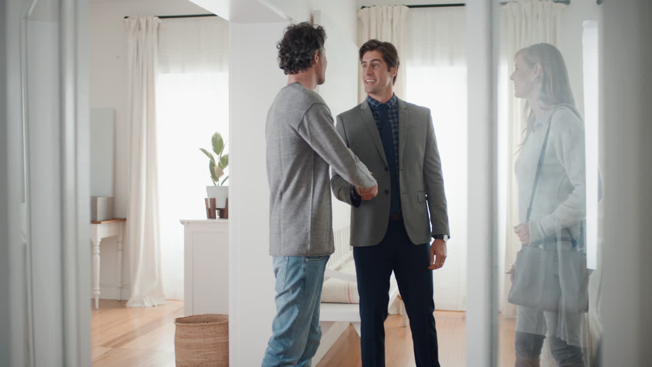 agente imobiliário mostrando jovem casal nova casa apresentando investimento imobiliário clientes felizes apertando as mãos com corretor imobiliário comprando com sucesso casa 4k filmagem