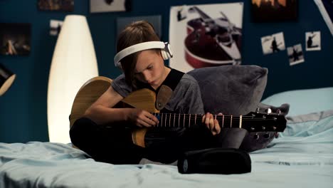 boy in headphones learning song with guitar