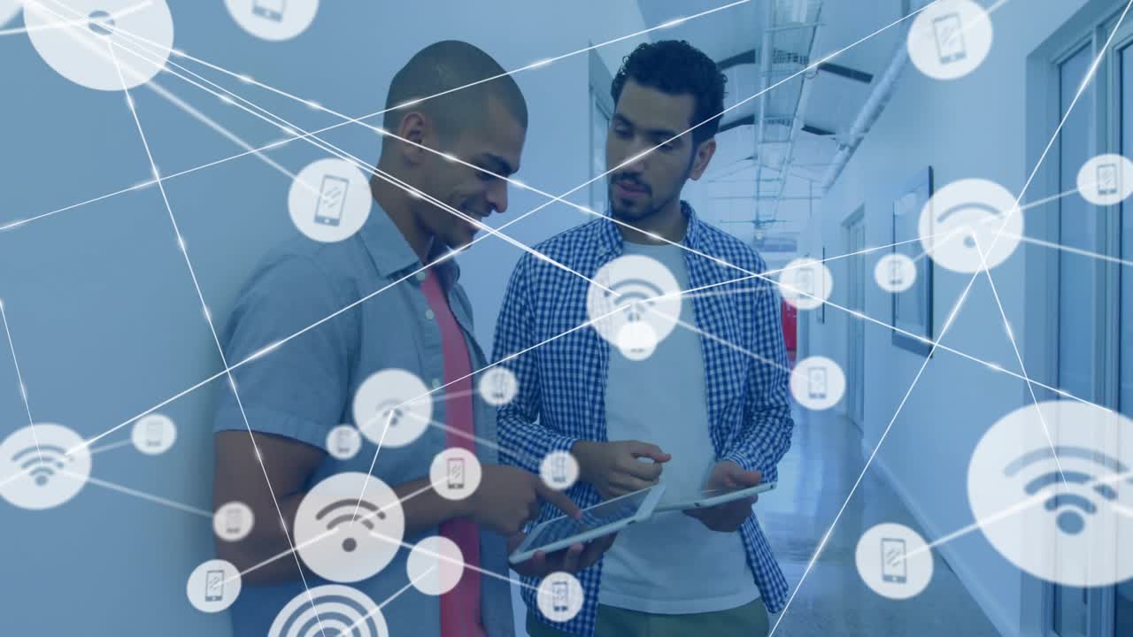 Two IT professionals leaning office wall pointing at tablet, showing network graphics overlay