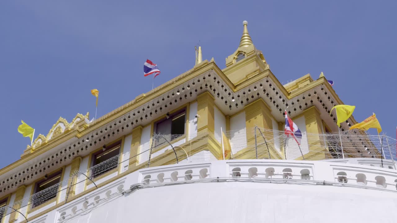 Pan over Golden Mount Temple in Thailand with waving Thai flag