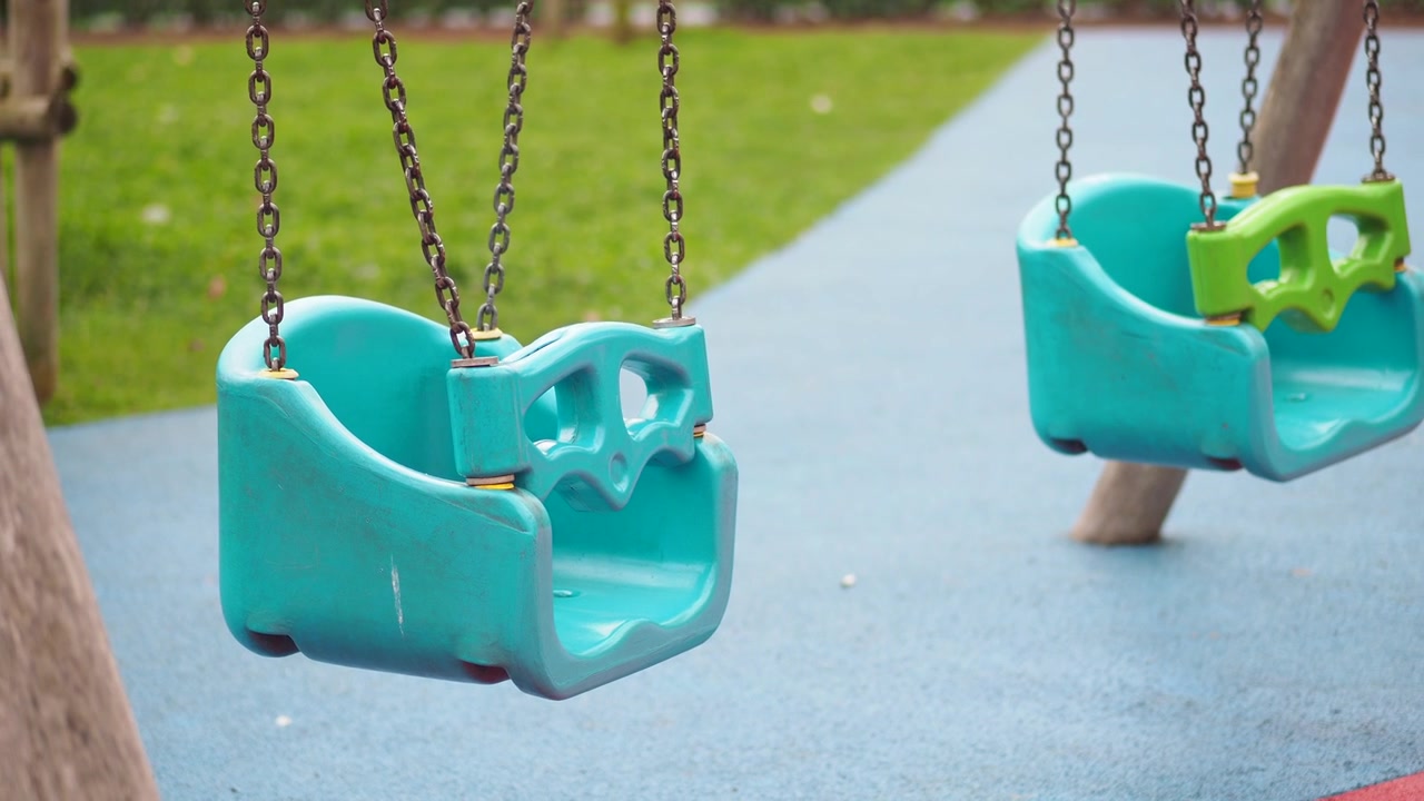 Altalene per bambini vuote che si muovono delicatamente in un parco giochi