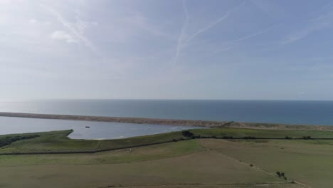 Seguimiento-Aéreo-Hacia-Arriba-Detrás-De-La-Increíble-Laguna-De-La-Flota-Y-La-Playa-De-Chesil-En-Abbotsbury,-Dorset