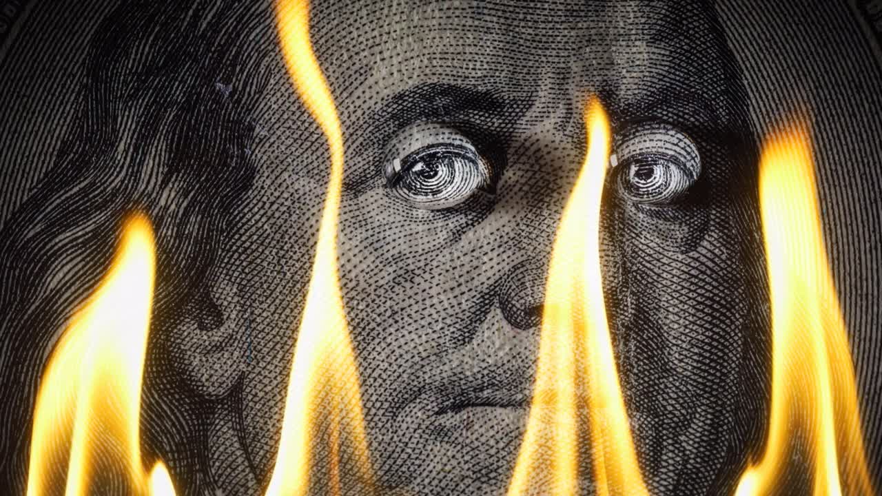 Portrait of Benjamin Franklin on a hundred dollar bill on fire in flames. Conceptual 4k slow motion video. The idea of ​​a financial crisis.