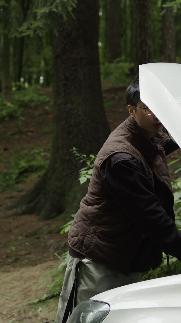 Man working on a car in the woods