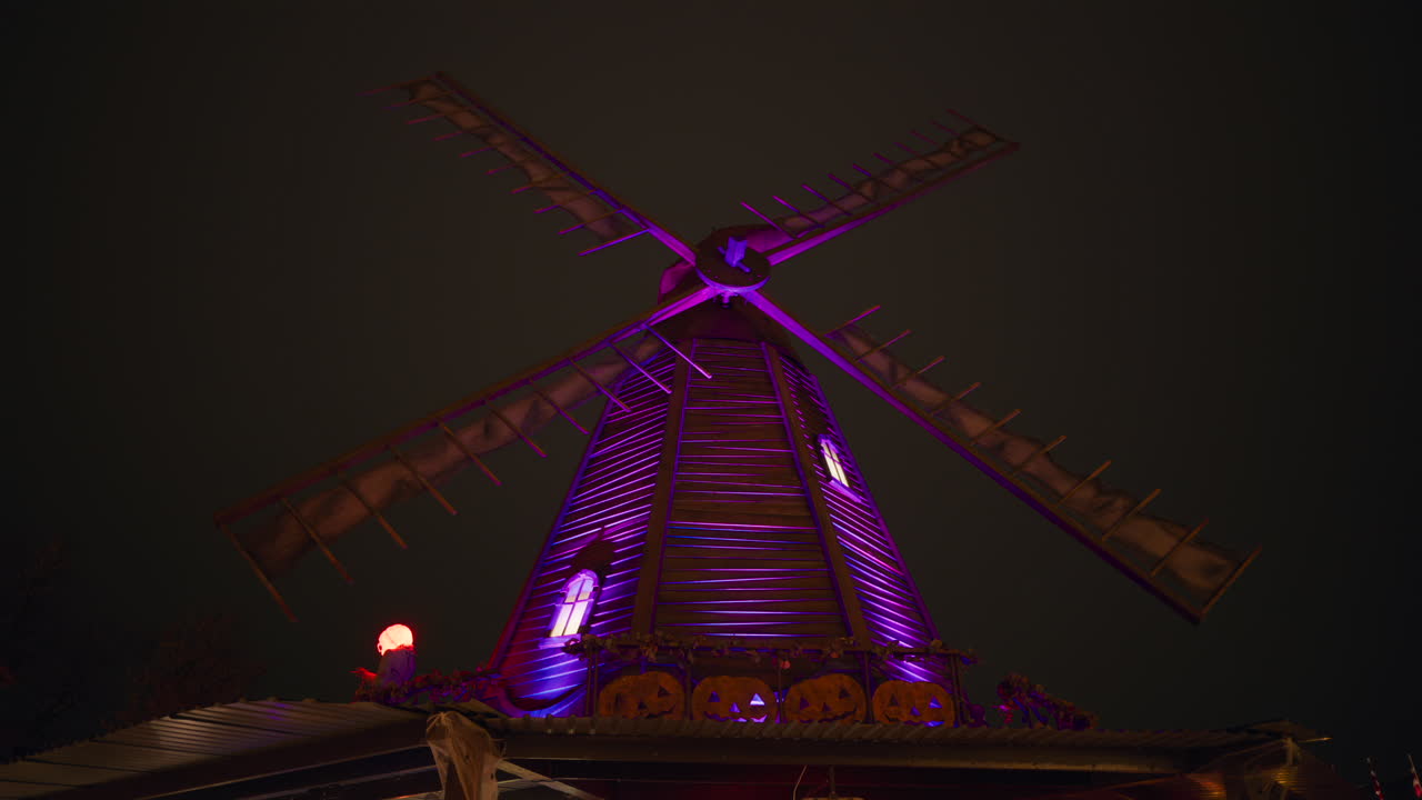 View of a purple lit wind mill, decorated for Halloween at the Tivoli Gardens amusement park in Copenhagen, Denmark, at night