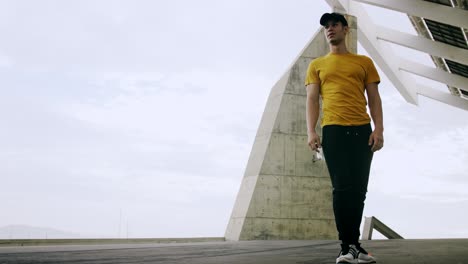 Young-Attractive-Trendy-Man-skateboarding-fast-under-a-solar-panel-on-a-morning-sunny-day-with-an-urban-city-background-in-slow-motion