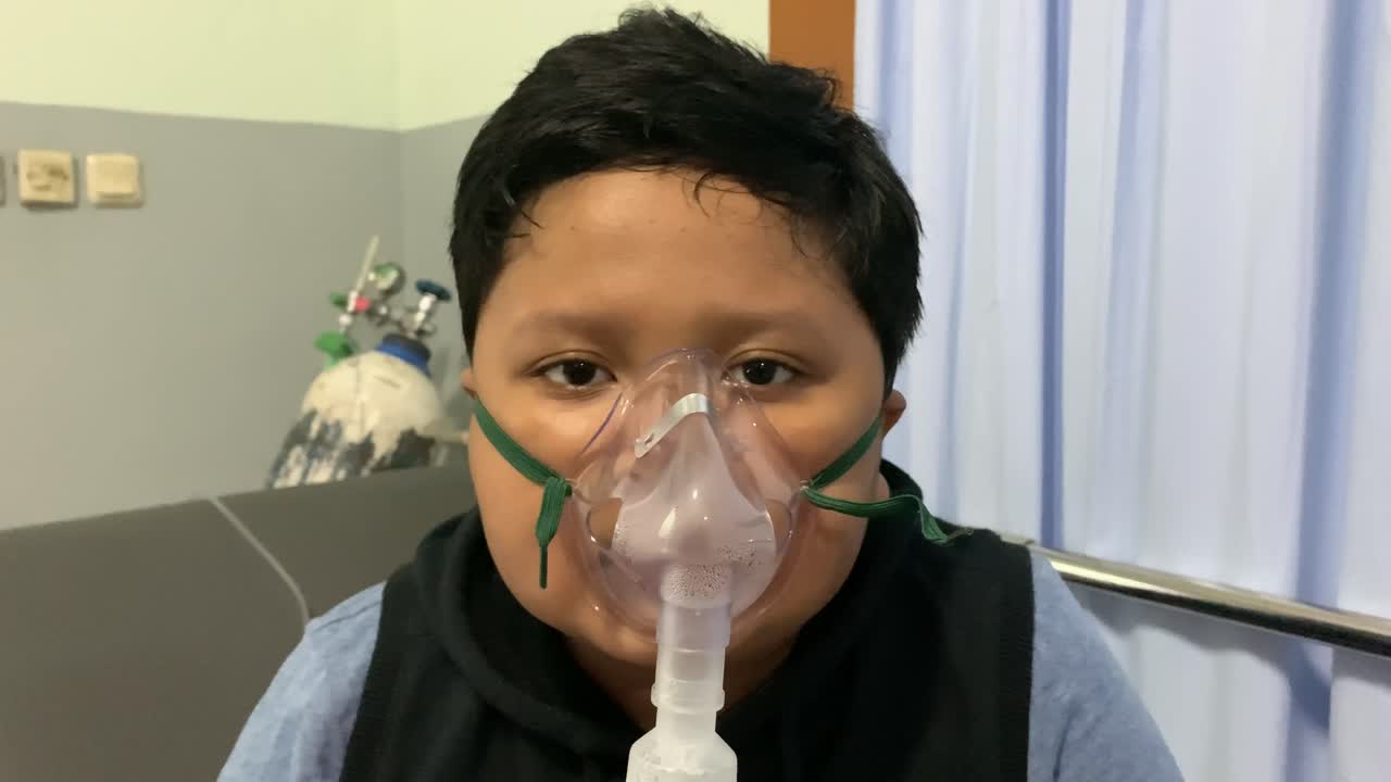 chico asiático hace inhalación con nebulizador en el hospital