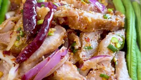 Sliced pork with red onion, dried chili, and fresh long beans in a vibrant, spicy presentation.