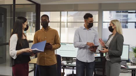 Group-of-diverse-businesspeople-wearing-face-masks-and-discussing-together