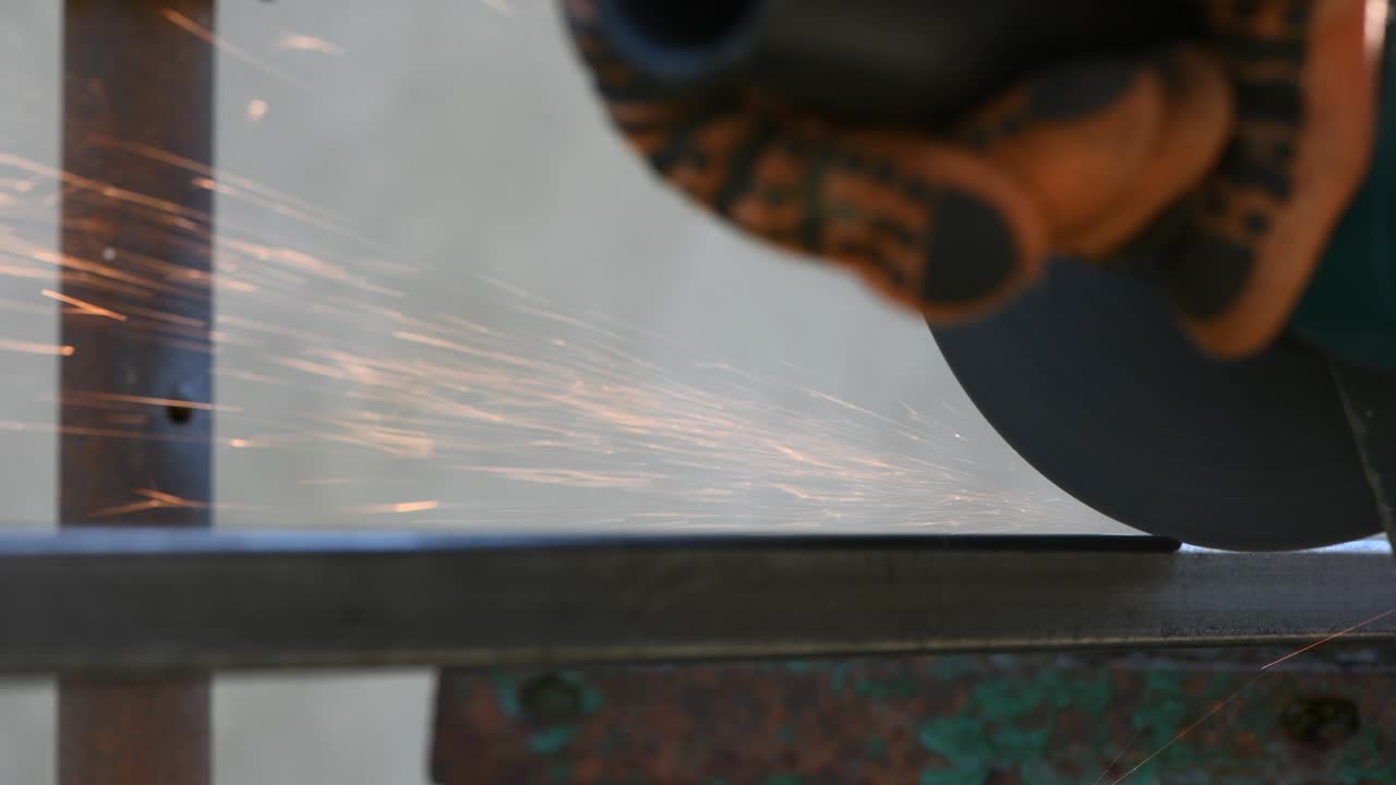 человек работает на угловой мельнице. из горячего металла летают искры.