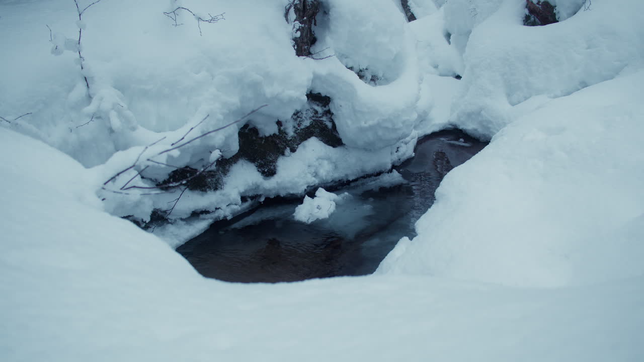 un arroyo helado que fluye en medio de profundos bancos de nieve en la laponia finlandesa