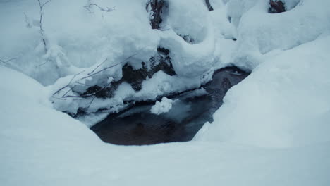 icy creek streaming in the middle of deep snow banks in finnish lapland