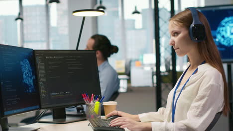 young female programmer in office reviewing ai system metrics, listening music