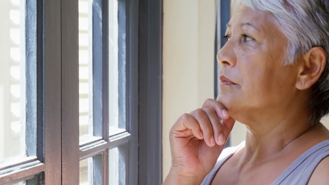4kの寝室の窓から眺める思慮深い年配の女性