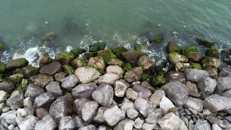 Aerial-view-above-splashing-tide-on-rocky-UK-EU-coastline-slow-dolly-right