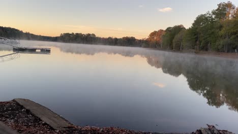 early morning fog rolling over calm water of southern lake
