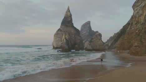 man running on a beach surrounded by rocks and cliffs