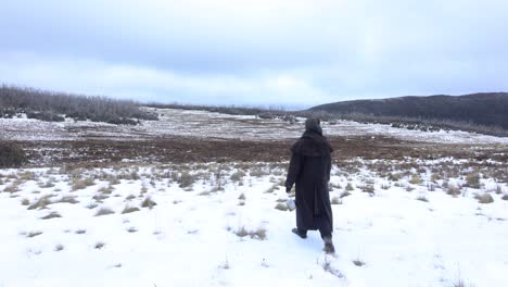 a wide shot of a bushman walking into the landscape of a snowy mountain in the victorian high country