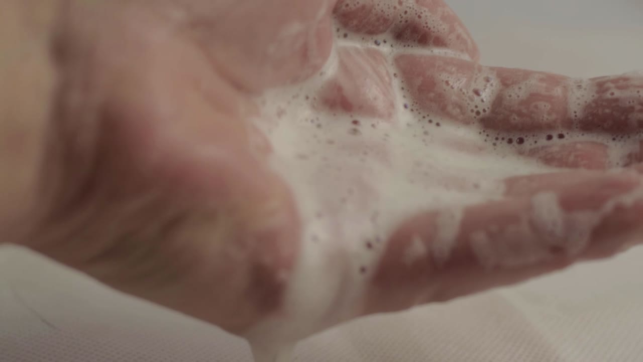 Hands with soapy water suds dropping macro shot