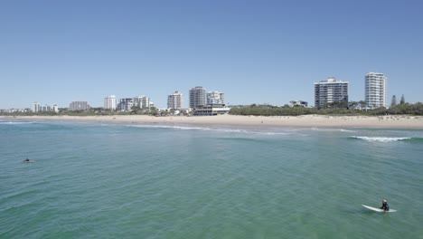 surfers in maroochydore beach with beachfront hotels in sunshine coast, qld, australia