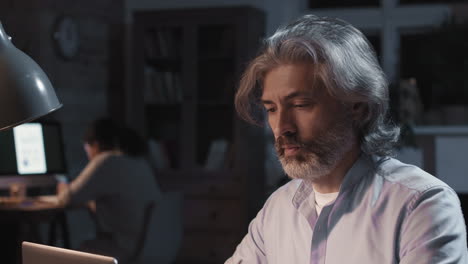 tired mature man working late at night in office