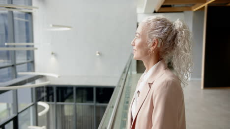 looking out office window, businesswoman with curly hair contemplating future projects, copy space