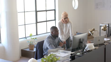 collaborating on project, colleagues discussing work at office desk with computer