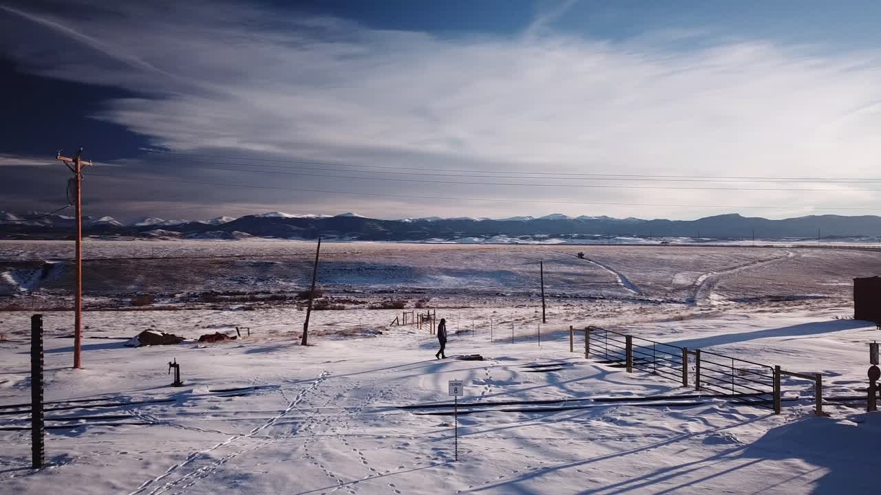 Pan of man walking forward on snow into rocky mountain backdrop