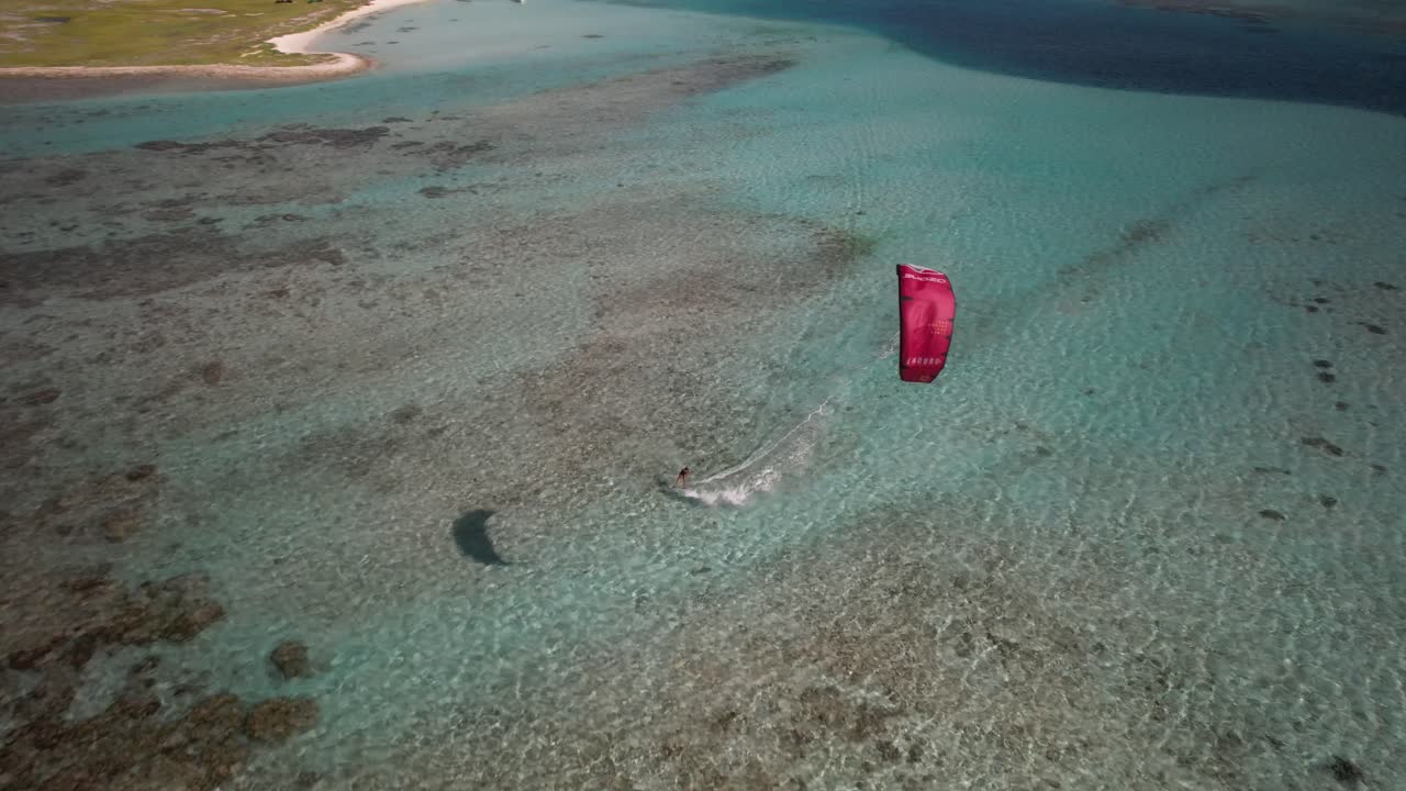 kitesurfista deslizándose en aguas cristalinas de color turquesa, vista aérea