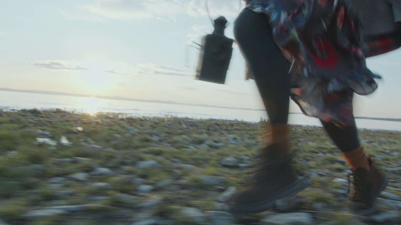 해가 지면 호수 연안 을 따라 달리는 손 에 등불 을 들고 있는 젊은 여자