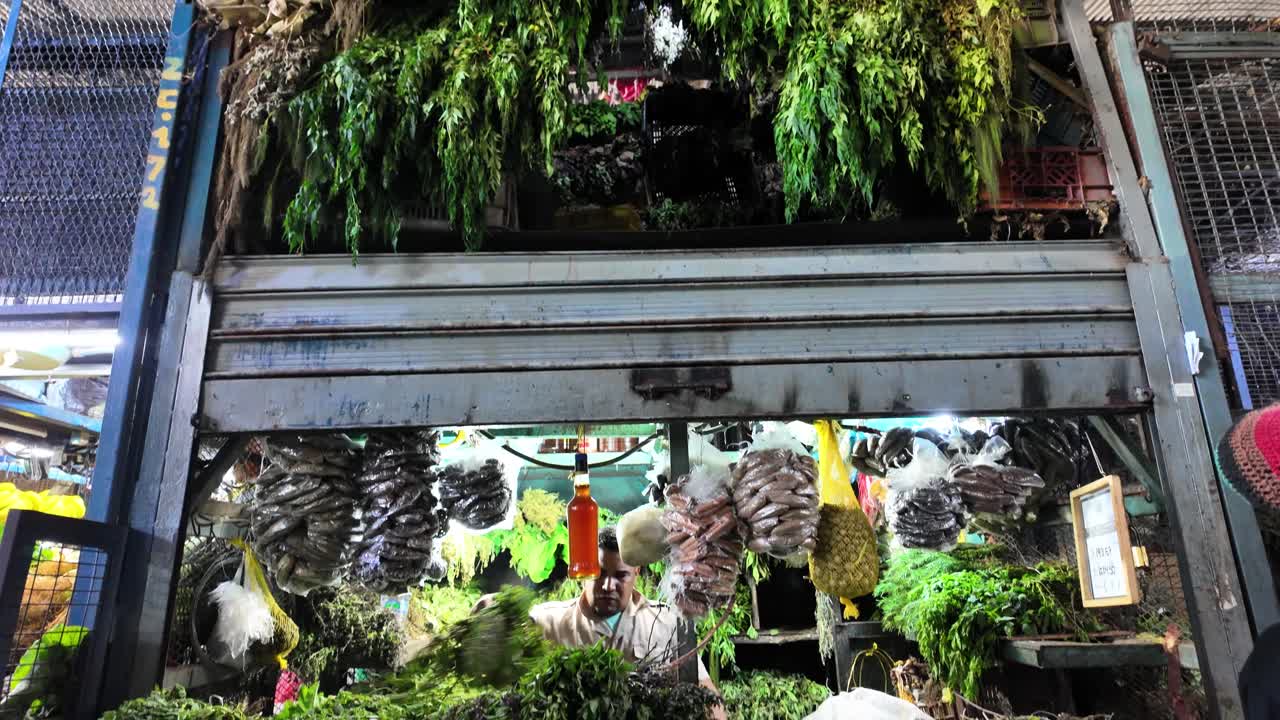 Vendor working at market stall filled with abundant fresh medicinal herbs. Latin American culture