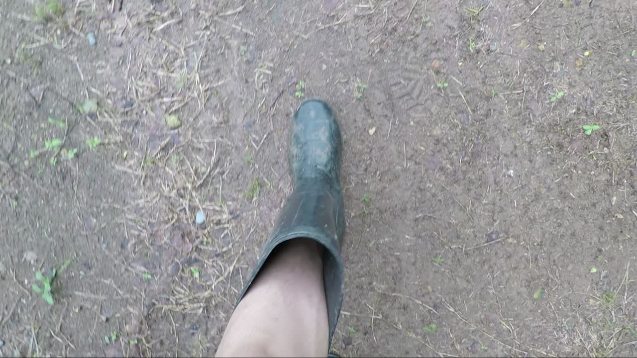 pov de un hombre con botas negras caminando mirando hacia abajo en un camino fangoso