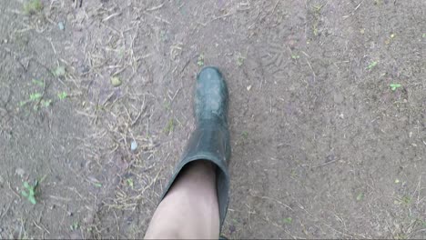 pov of a man wearing black boots walking looking down on a muddy road