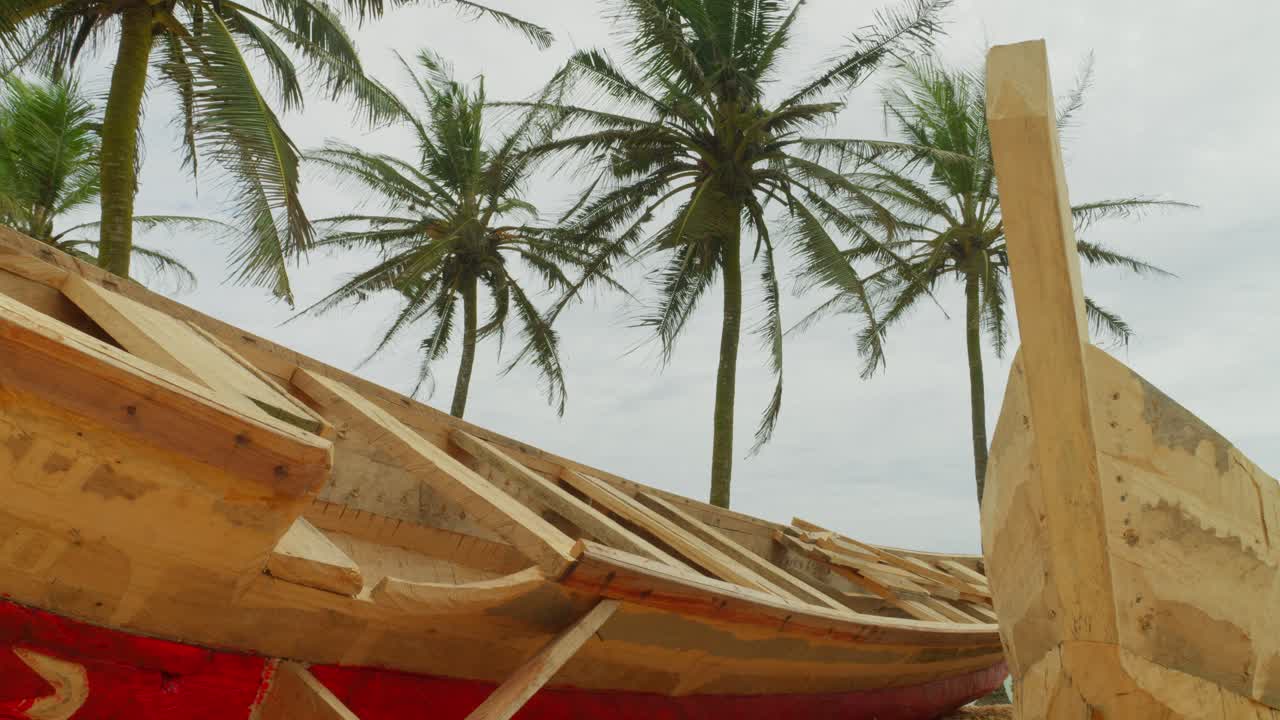nuevo barco tradicional africano de pescadores de madera colocado en la playa de arena tropical de ghana con palma