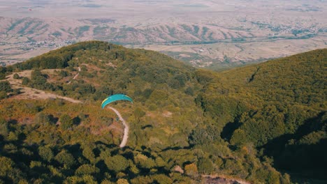 Drohnenaufnahme-Eines-Gleitschirms,-Der-über-Einem-Immergrünen-Wald-Fliegt