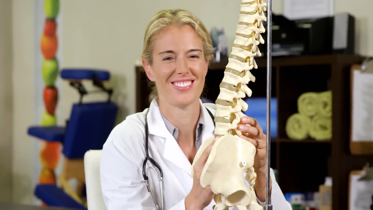 fisioterapeuta mirando el modelo de la columna vertebral