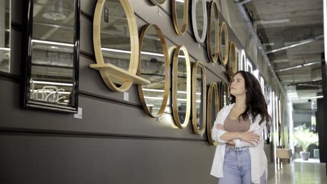 a young woman exploring wooden decor and round mirrors in a modern furniture store a young woman exploring wooden decor and round mirrors in a modern furniture store