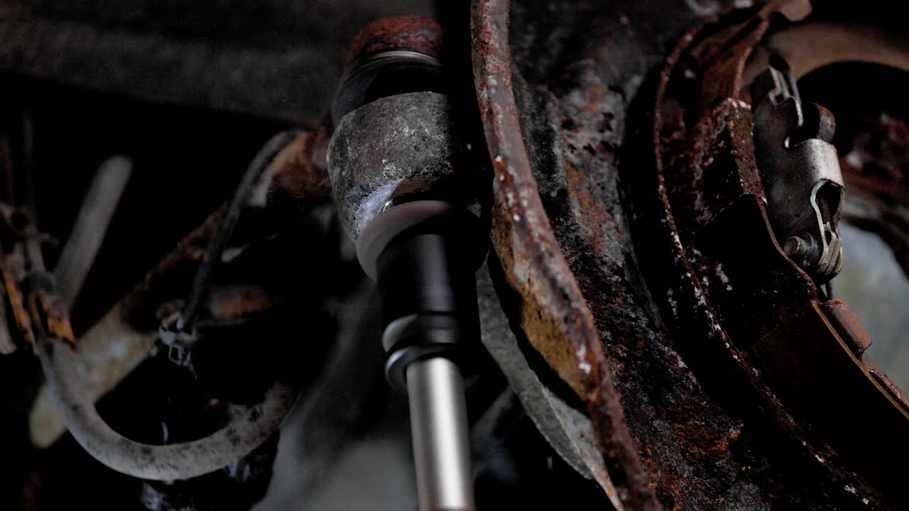 Close up of impact gun removing a nut off a rusty suspension control arm of a car. Static shot in 4k.