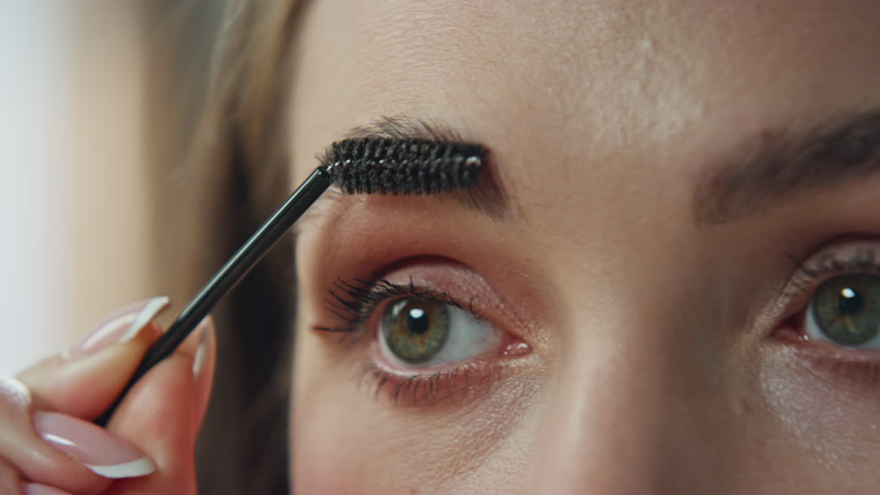 Close-up of a woman applying makeup on her eyebrows
