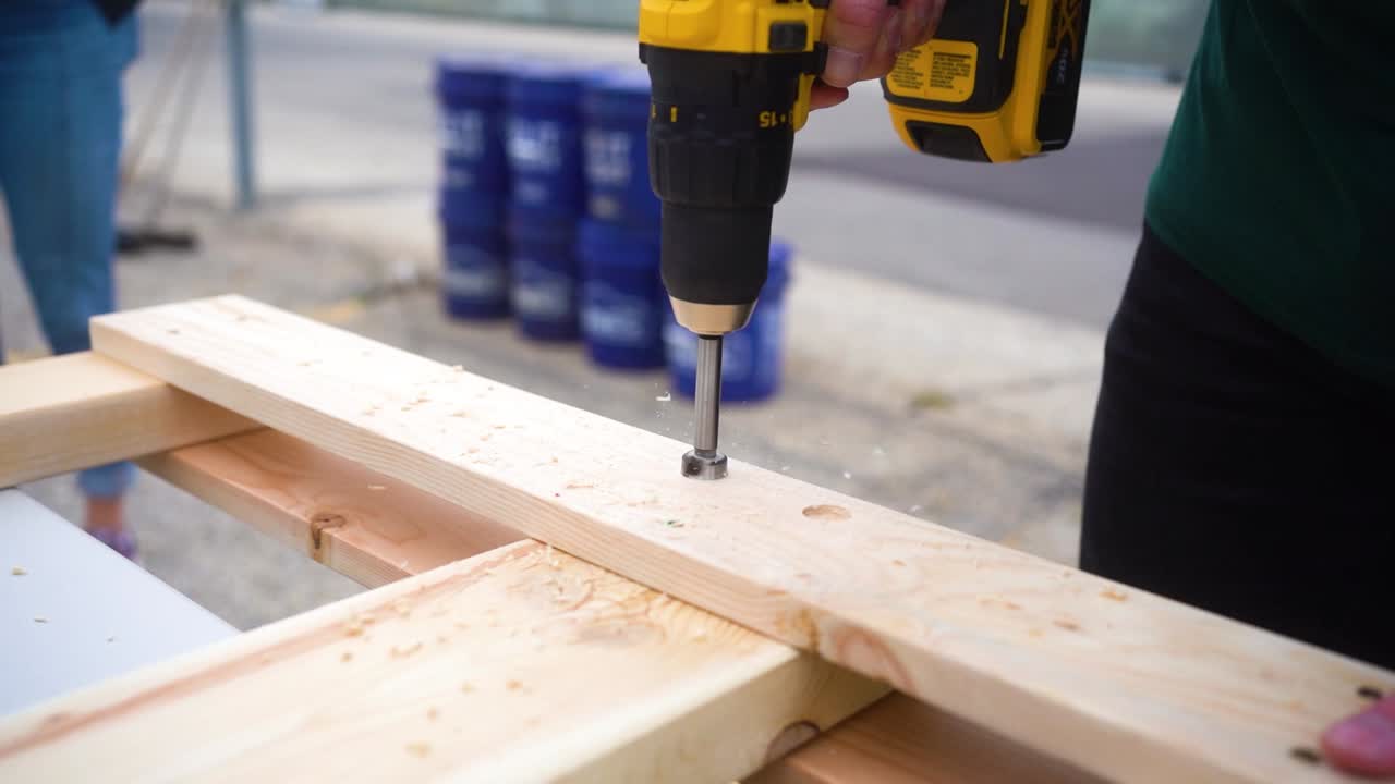 Person using a drill to assemble a wooden structure