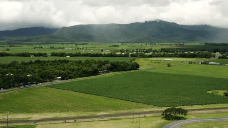 Aerial-trucking-shot-of-lush-green-landscape-of-Australia-with-mystic-clouds-covering-mountain-peaks