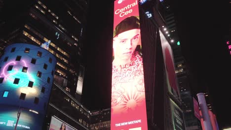 luminous time square advertising at night in new york city - light camara driving forwards - a street sign passes by