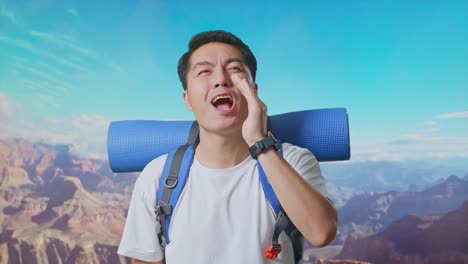 close up of asian male hiker with mountaineering backpack screaming holding hands near his mouth while traveling at the top of mountain