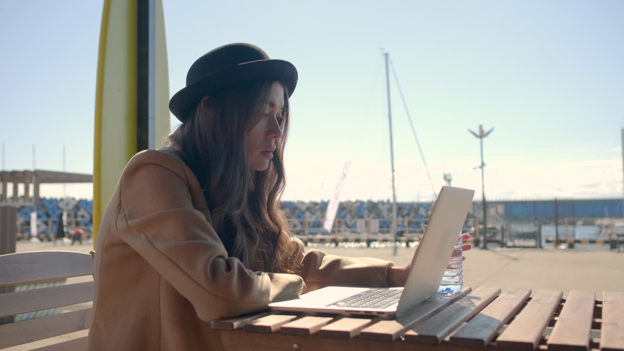 mujer trabajando en una computadora portátil en un café frente al mar