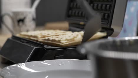 Removing-Hot-Cooked-Waffles-From-Iron-Waffle-Maker---close-up