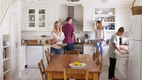 family with teenage children preparing breakfast in kitchen